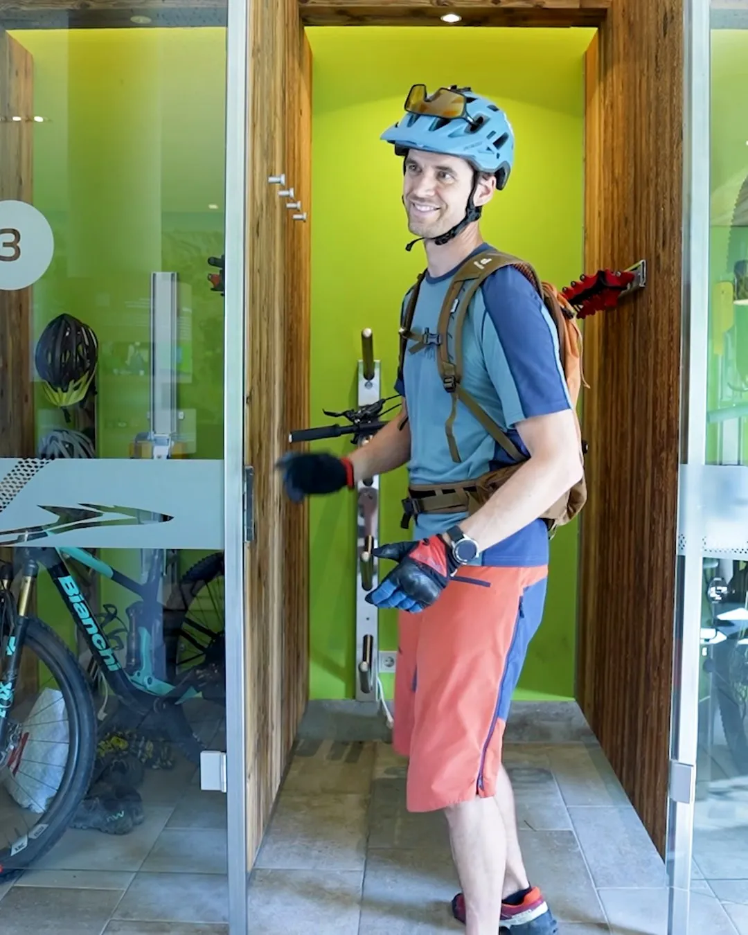 Thilo lächelt mit Bikehelm beim Abstellen seines Mountainbikes im Bike-Raum des Explorer Hotels