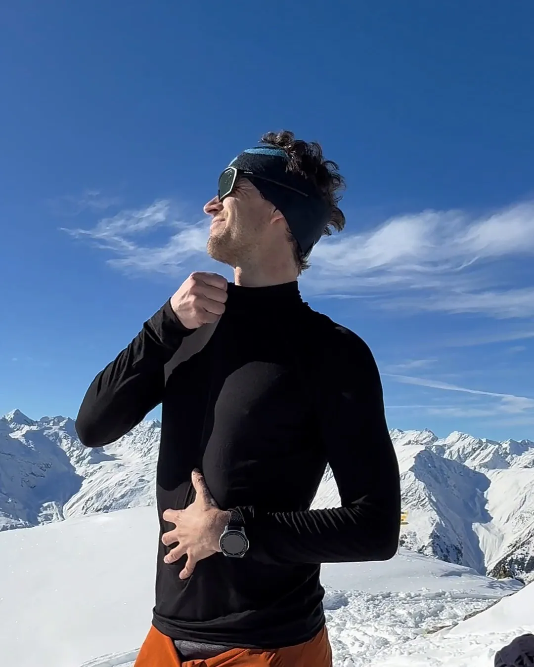 Thilo im mey-Funktionsshirt am Gipfel vor verschneiten Bergen
