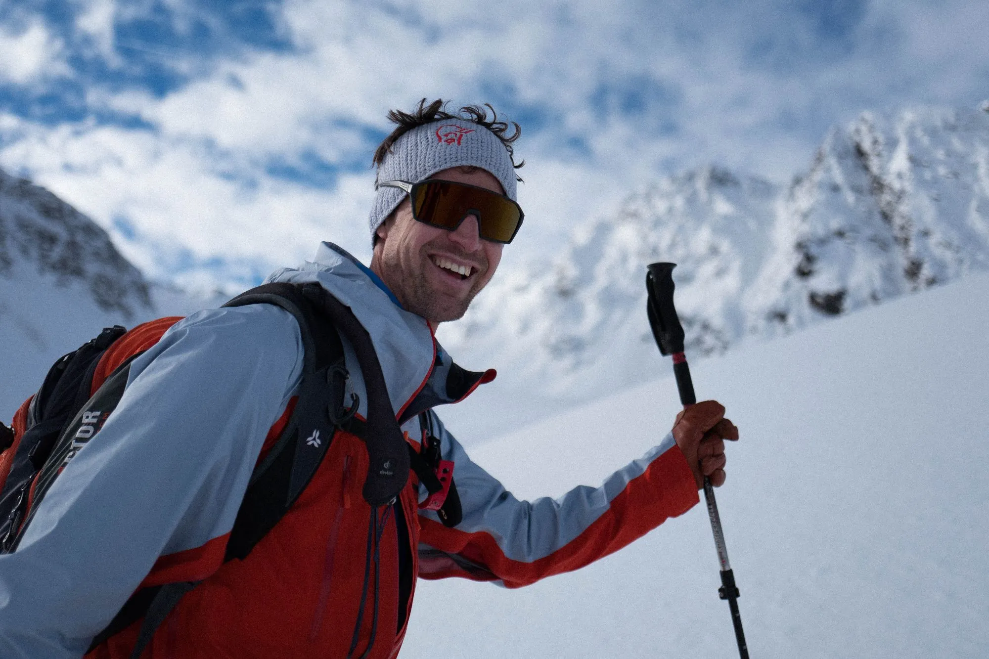 Thilo lachend beim Aufstieg mit Tourenski, Rucksack und Stöcken