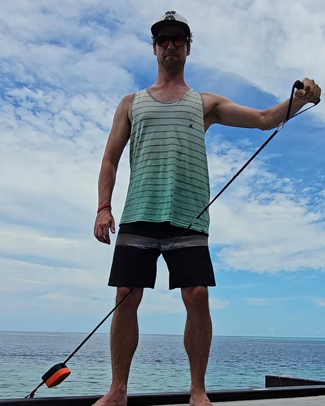 Thilo trainiert auf einem Holzsteg am Meer mit dem PUMP-Seilzuggerät, das Gerät liegt vorne auf dem Steg