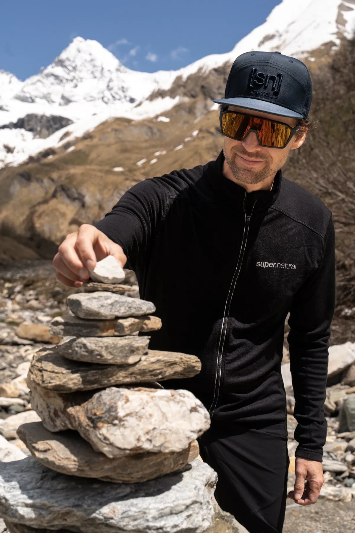 Thilo in super.natural-Merinojacke baut ein Steinmandl vor dem Großglockner