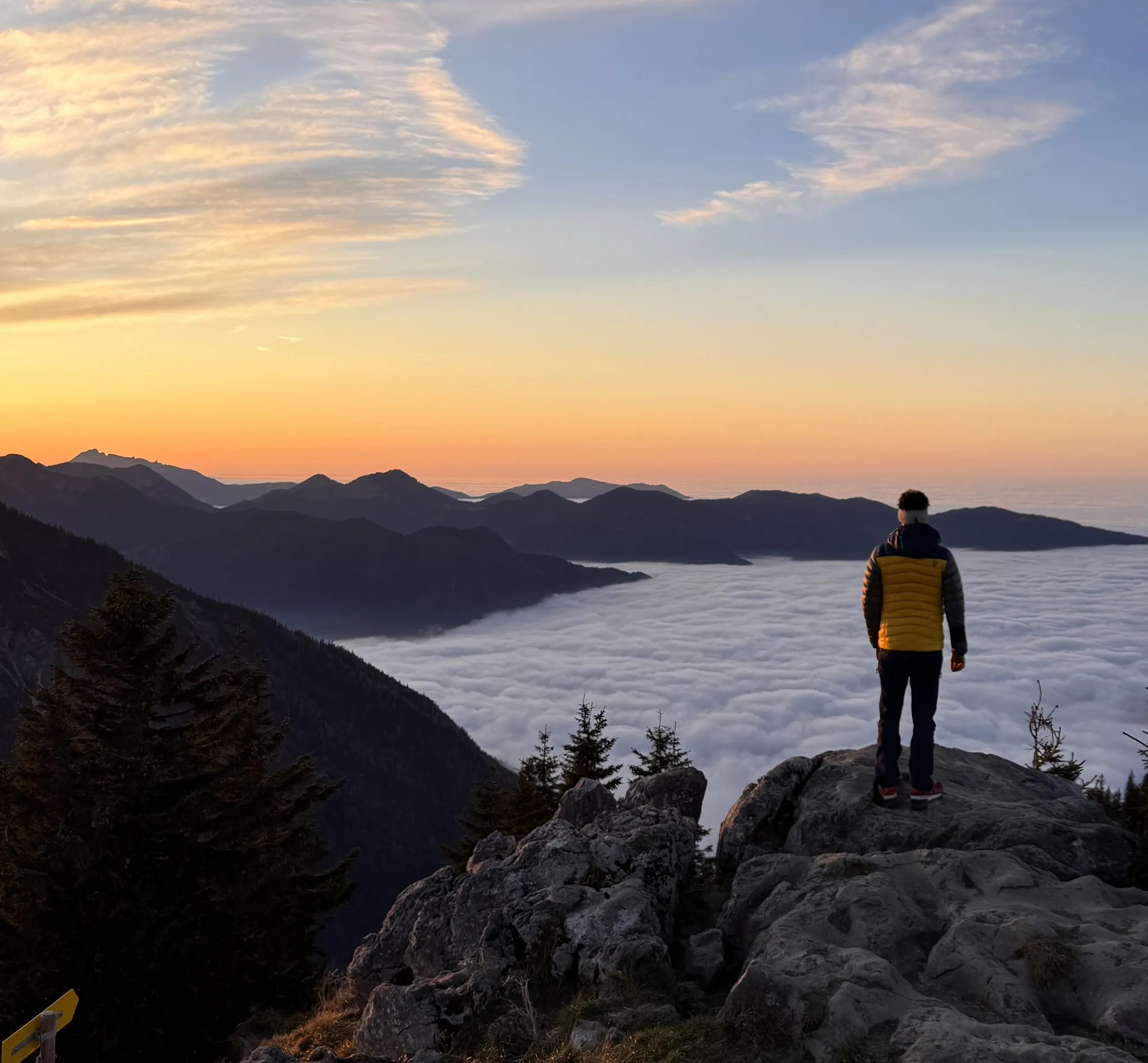 Thilo steht bei Sonnenaufgang auf einem Felsen über dem Nebelmeer